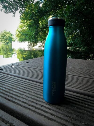 Eine blaue 720°DGREE Edelstahl Trinkflasche “milkyBottle” Thermosflasche auf einem Steg