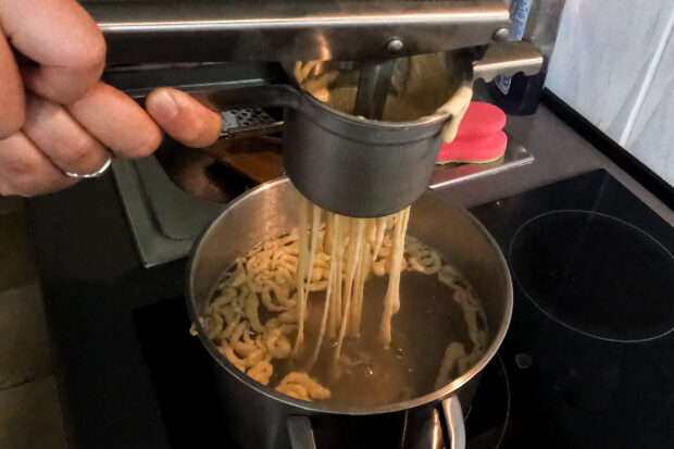 Spätzle Teig wird durch die Heimstory Spätzlepresse in den Topf gepresst