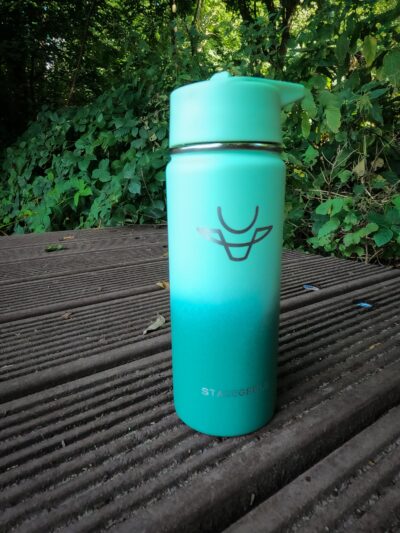 Eine türkise STACEGEELE Thermosflasche auf einem Steg