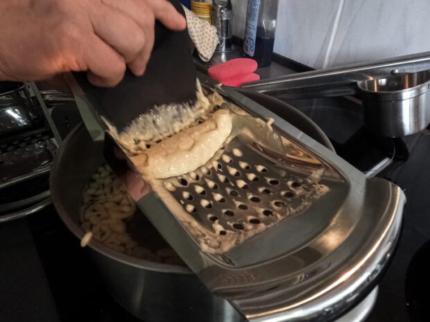 Die WMF Reibe bei der Herstellung von Spätzle auf einem Topf