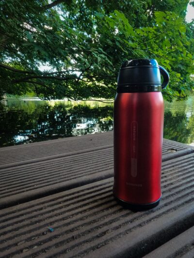 Eine rote Y·J&H vakuumisolierte Edelstahltrinkflasche Thermosflasche auf einem Steg